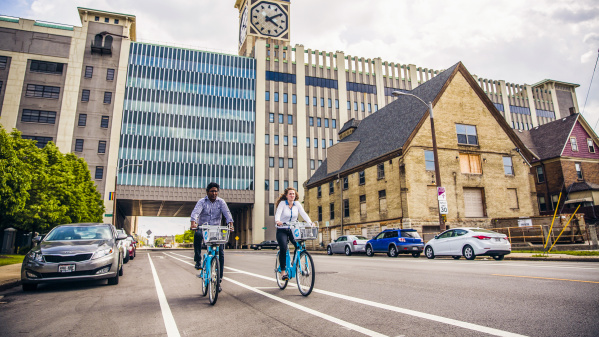 two people using bublr bikes, biking under the clocktower