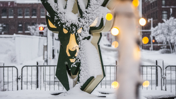 statue of the Milwaukee Bucks logo in snow with holiday lights