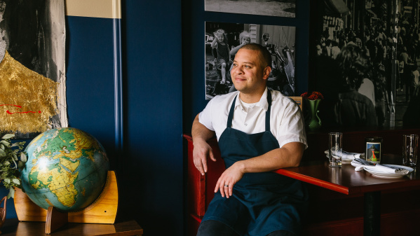 a chef sitting on a chair at a dining table in a restaurant