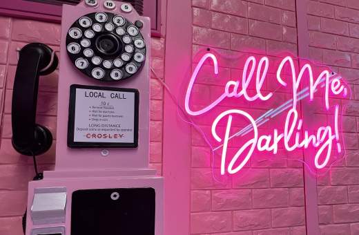pink wall telephone beside a pink neon sign