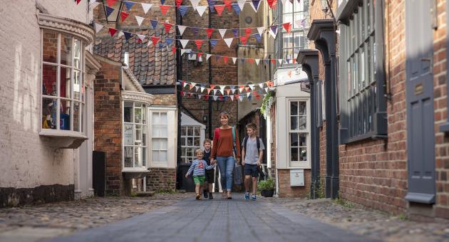 a family walking along a side street with bunting hanging from the buildings