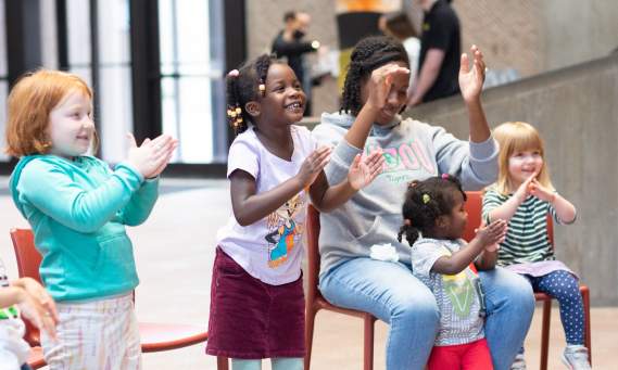 kids and one adult clapping along to a program at the Everson