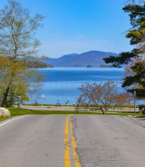 People biking along Beach Road with a view of Lake George