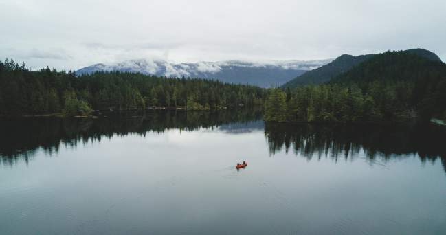 Aerial view of two people paddling a canoe across the lake.