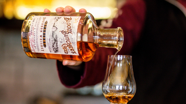 A bartender pouring a snifter of bourbon at Jeptha Creed Distillery in Shelbyville, KY
