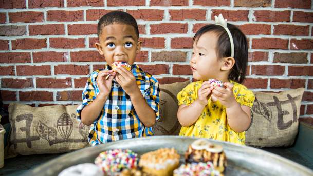 2 kids eating donuts