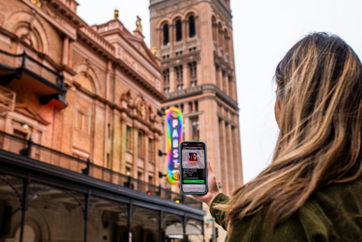 woman holding phone up in front of building