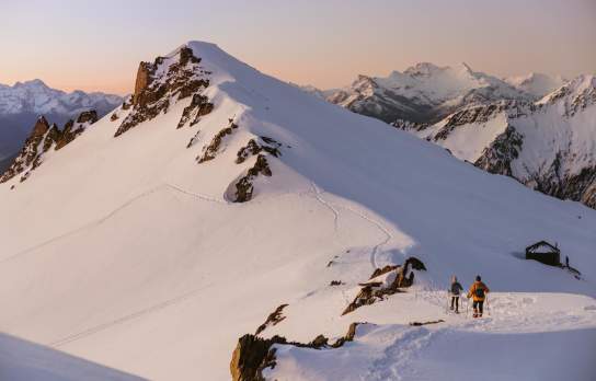 People snow shoeing across snow covered mountain peaks