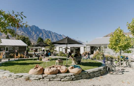 A collection of boutique shops and people sitting around a green park