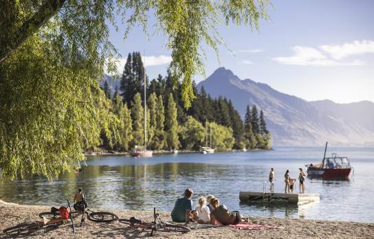 Family sitting by the lake at Queenstown Bay on a summer's day