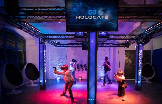 A group of people standing in a colour virtual reality area wearing VR sets