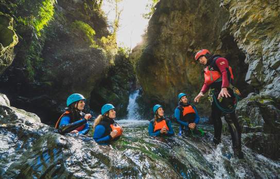 Group of people in wetsuits and helmets in the middle of a canyon