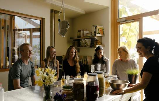A group of people sitting around a kitchen island during a food workshop