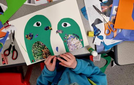 Top down view of a child making bird art out of paper cut outs