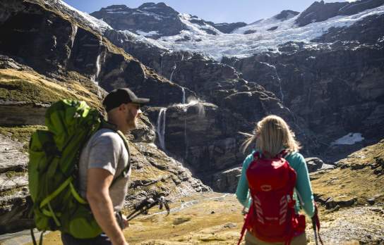 Couple hiking underneath glacier at Earnslaw Burn