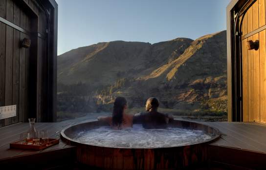 Two people in a hot tub with a beautiful mountain view