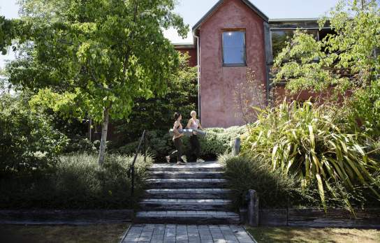 Two women walking outside a health centre holding yoga mats.