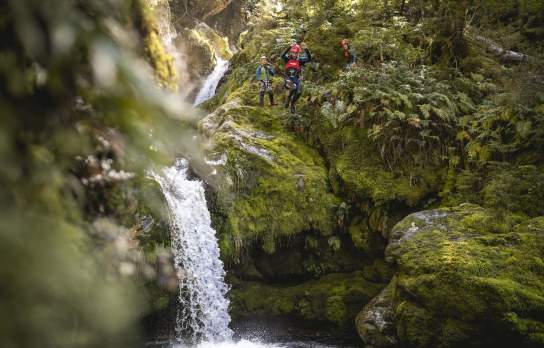 Person canyoning, jumping off a waterfall into a natural spring