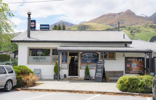 Exterior shot of Glenorchy hotel and pub which old school signage and mountains in the background