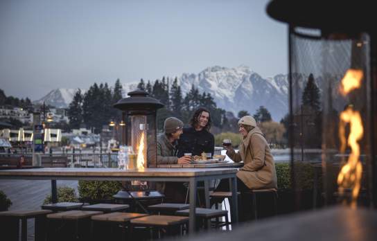 Friends dining outdoors in winter with Remarkables mountain in the background