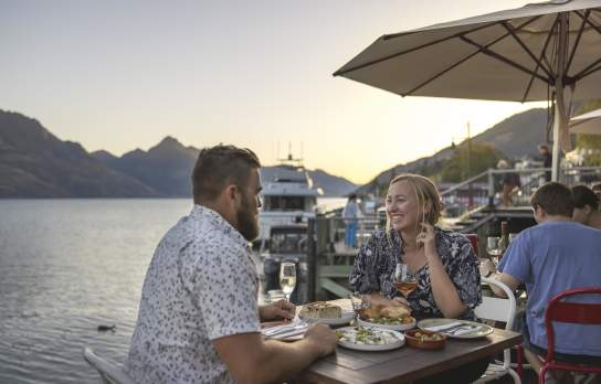 People dining by the lake with mountains in the background