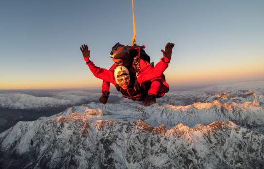 Skydiver high above snowcapped mountains of Queenstown
