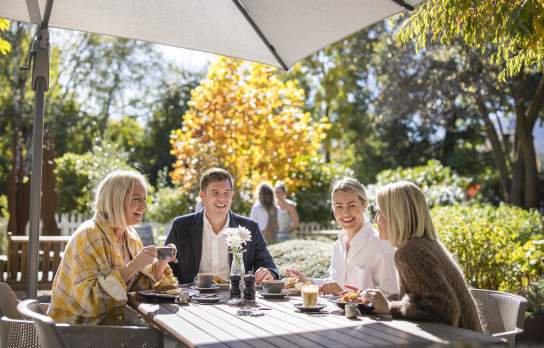 Group of people enjoying breakfast outside on a sunny autumn day