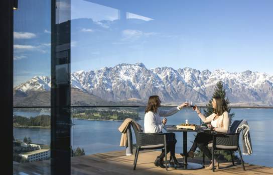 People dining outside with snow capped mountains in the background