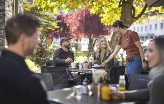 Waitress serving customers in a pretty outdoor autumn setting