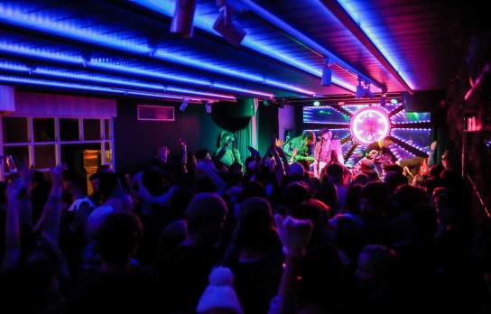 Crowd partying to live music stage with colourful lights at Yonder at night