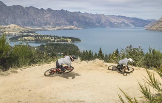 Bikers riding Queenstown Bike Park in Queenstown with Remarkables Mountains in the background
