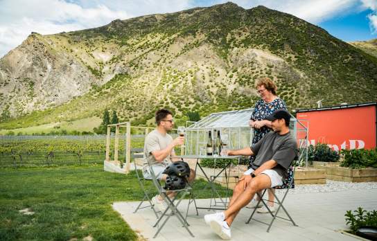 People enjoying a wine at ta table with mountains in the background