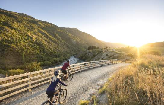 Couple cycling the Gibbston River Wine Trail