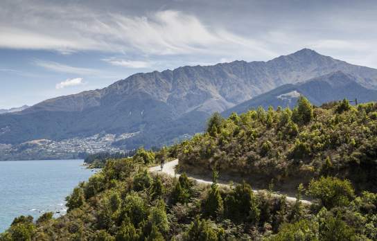 Person biking Jack's Point Trail, with Queenstown and Ben Lomond mountain in the background