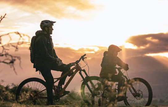 Silhouette of father and son on mountain bikes at sunrise