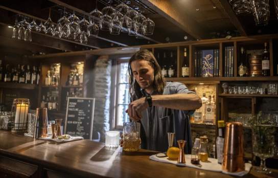 Bartender mixing a cocktail at The Blue Door bar in Arrowtown.