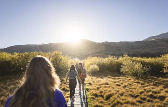 Photo from the point of view walking along the Glenorchy walkway with mountains and the rising sun ahead