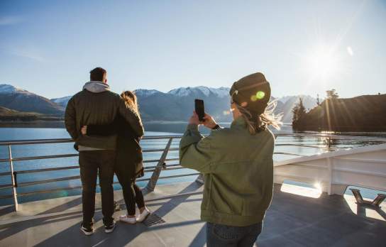 Person taking a photo of a couple on the Spirit of Queenstown Lake Cruise, Southern Discoveries