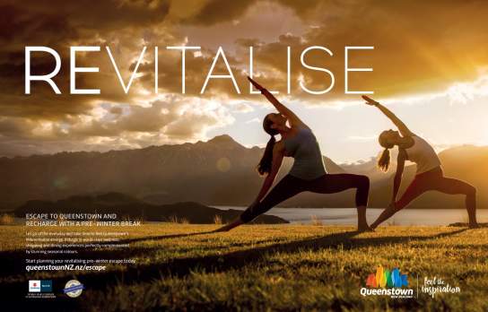 Two people are practising yoga outdoors at sunset on a grassy hill, with mountains and a lake in the background. The text reads “REVITALISE” and promotes a pre-winter escape to Queenstown, New Zealand.