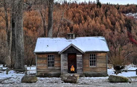 Person sits outside histroric Police Hut Arrowtown