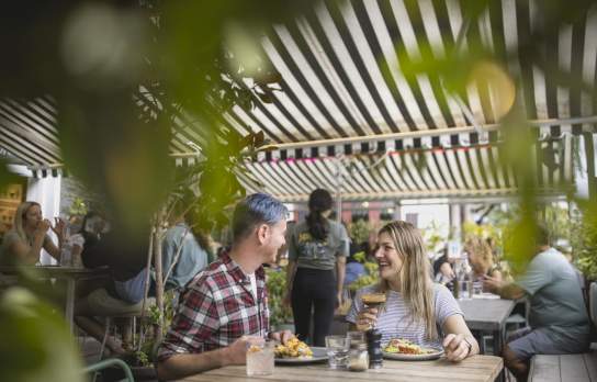 A couple sat at a table enjoying cocktails and brunch at Yonder cafe in Queenstown