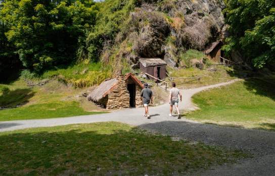 People exploring the historic Chinese Village huts in Arrowtown