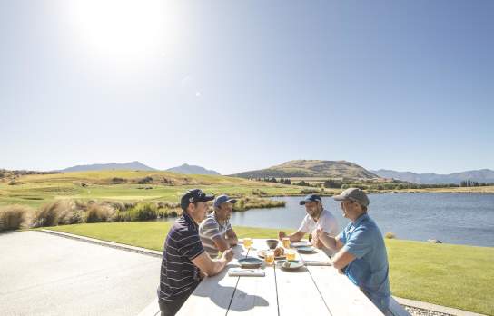 Ground of friends eating outdoors next to lake and mountains