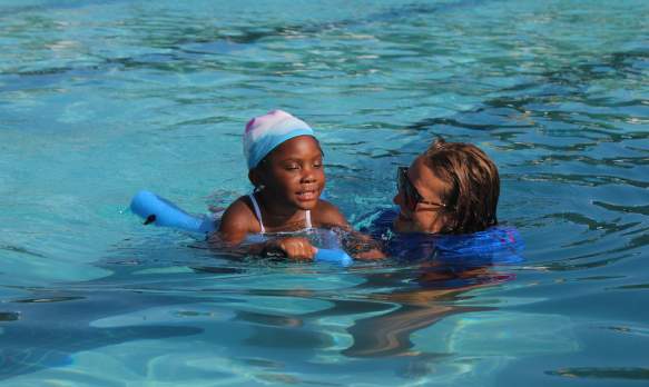 Young girl participating in swim lessons with a swim instructor.