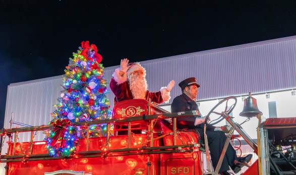 Santa waving while riding down the Holiday Festival Parade in Downtown Salina, Kansas
