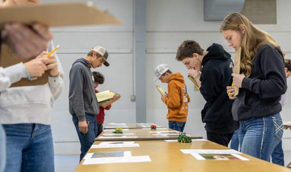 A group of young adults look at papers on a long table at 2026 Farm Expo in Salina, Kansas