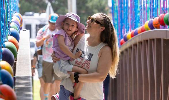 A mom and their kid crossing a colorful bridge at Smoky Hill River Festival in Salina, Kansas.
