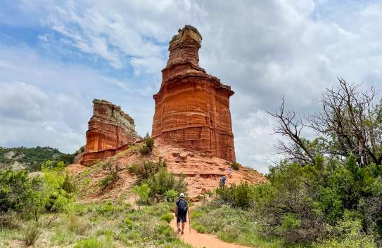 Man walking up to the beautiful red sandstone lighthouse rock structure (hoodoo) on a sunny day