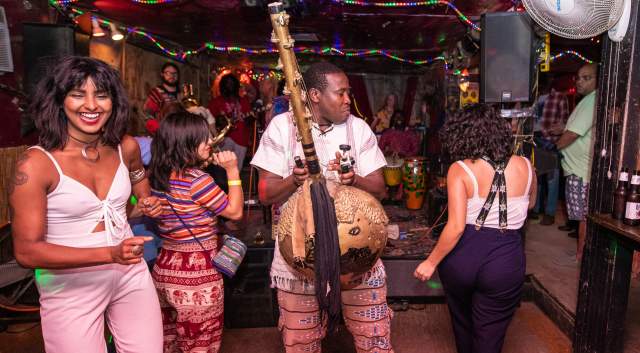Men and women dancing at Sahara Lounge to a man playing a traditional African instrument.