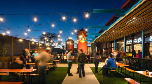 Evening patio at Austin Beerworks with string lights and people standing around the tables